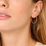 A single silver-toned hoop earring, encrusted with clear crystals on its outer curve.