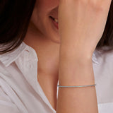 White-plated bracelet with a single row of small, clear, round stones set along its entire length.