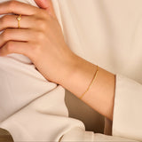 Thin gold-toned chain bracelet with a central straight line of tiny, sparkling elements.