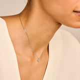 Silver-toned necklace with a thin chain and a small, four-petal flower pendant set with clear stones.