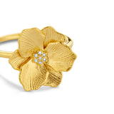 Gold-toned ring with a textured flower design featuring seven clear sparkling stones in the center.