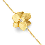 Gold-toned bracelet with a textured flower charm, featuring a cluster of small clear stones in its center, on a delicate link