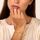 Gold-toned delicate chain bracelet with a jasmine flower charm featuring textured petals and a small clear stone in the cente