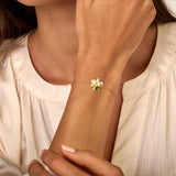 Thin gold-toned chain bracelet with a five-petal jasmine flower charm featuring a small clear stone in its center.
