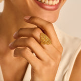 Gold-toned ring with a large, elongated, filigree-style top featuring a cluster of small, ornate circular patterns.