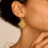 Gold-toned dangle earring with a fishhook. Features a square filigree design made of interconnected small circles and dots.