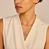 Silver-toned necklace with a square pendant featuring a floral pattern of small, round, silver-toned elements.