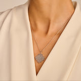Silver-toned necklace with a delicate chain and a square filigree pendant featuring an intricate floral pattern and small cle