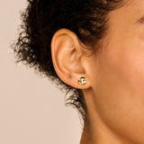 A single gold-toned poppy stud earring with three rounded petals and a small clear stone in the center.
