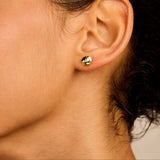 A single gold-toned stud earring shaped like a three-petal flower with a small clear stone in the center.