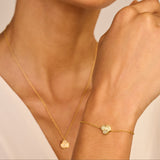 Gold-toned delicate chain bracelet featuring a central three-petal flower charm, each petal encrusted with clear stones.
