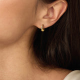 Gold-toned small hoop earring with a smooth, honey-drip shape and a single clear gem near the top.