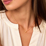 Thin gold-toned beaded chain necklace with small round beads spaced along it and a sparkling central bead.