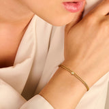 Gold-toned double-strand bracelet with one beaded chain and one smooth chain, centered with a round charm holding a clear sto