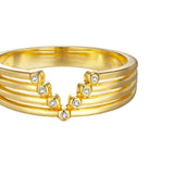 Gold-toned ring with three parallel bands forming a V-shape, featuring 7 small, round, clear stones.