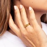 Gold-toned ring with four parallel bands merging into one, featuring a rectangular top section encrusted with small clear sto