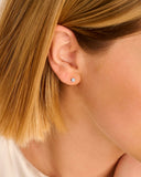 A single silver-toned stud earring shaped like a small flower, adorned with a cluster of clear stones.