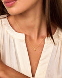 Small gold-toned necklace with a delicate chain and a flower-shaped pendant adorned with clear stones.