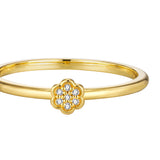 Gold-toned ring with a thin, smooth band. A small, raised, five-lobed flower design on top holds 7 clear, round stones.