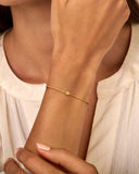 Delicate gold-toned chain bracelet with a small, sparkling flower-shaped charm in the center.