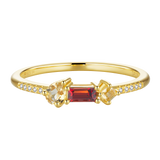 Gold-toned ring with a central dark red rectangular stone, flanked by a pear-shaped and a kite-shaped light yellow stone, wit
