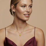 Gold-toned necklace with a delicate chain and a circular pendant featuring a textured, fan-like design.