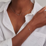 Delicate silver-toned curb chain necklace with a single small, round, clear stone set in the center.