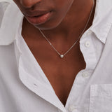 Delicate silver-toned necklace with a small, round pendant covered in pavé-set clear stones.