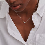 Delicate silver-toned necklace with a small, round pendant covered in pavé-set clear crystals.