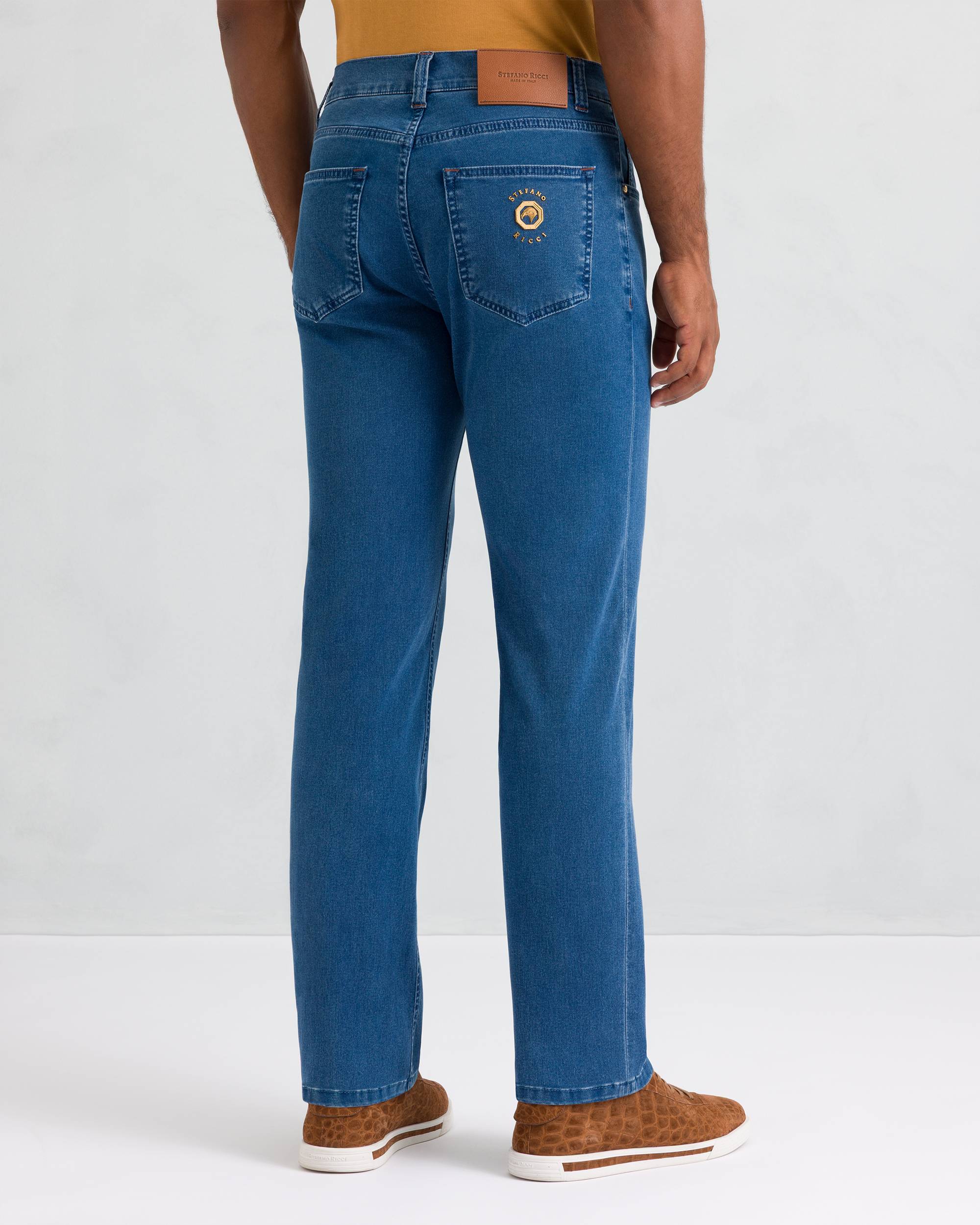Classic wash blue trousers with straight legs, two back patch pockets, a gold-toned emblem on the right, and a brown back pat