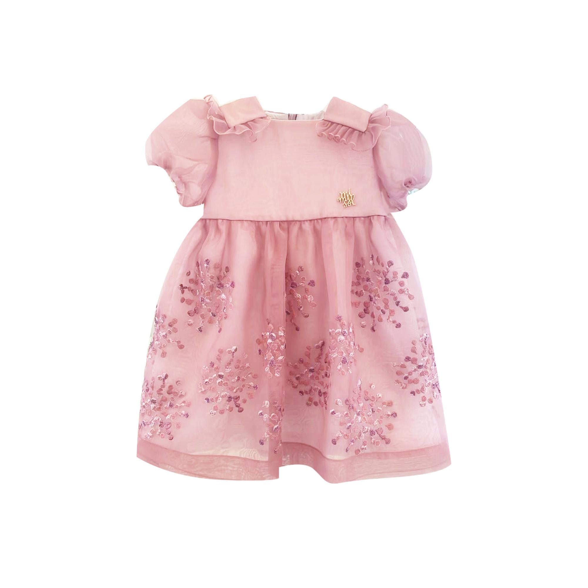 Pink baby dress with ruffled collar, puff sleeves, gold-toned emblem, and a sheer skirt embellished with pink sequins.
