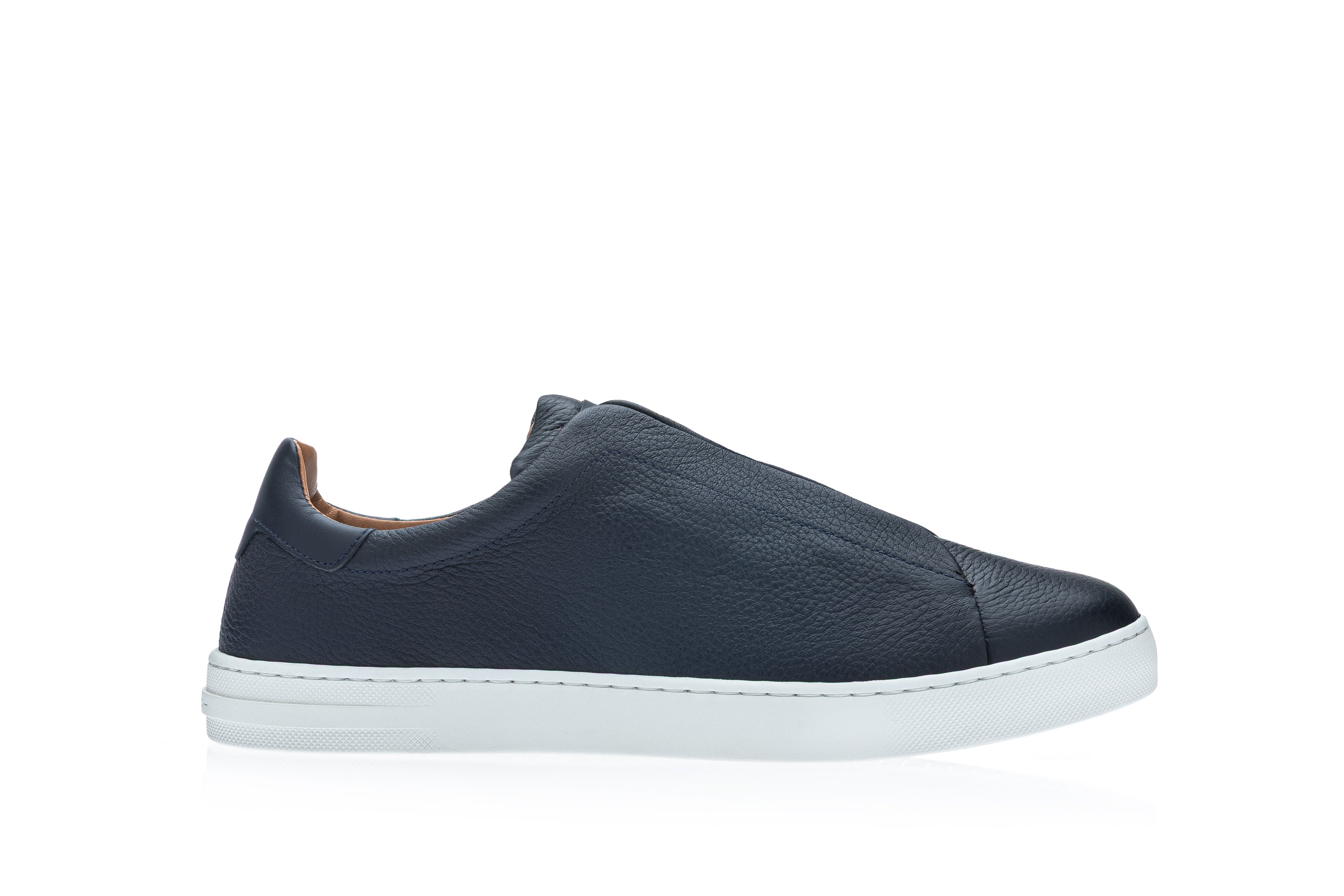 Dark blue pebbled leather slip-on sneaker with a smooth heel tab and a thick white rubber sole, viewed from the side.