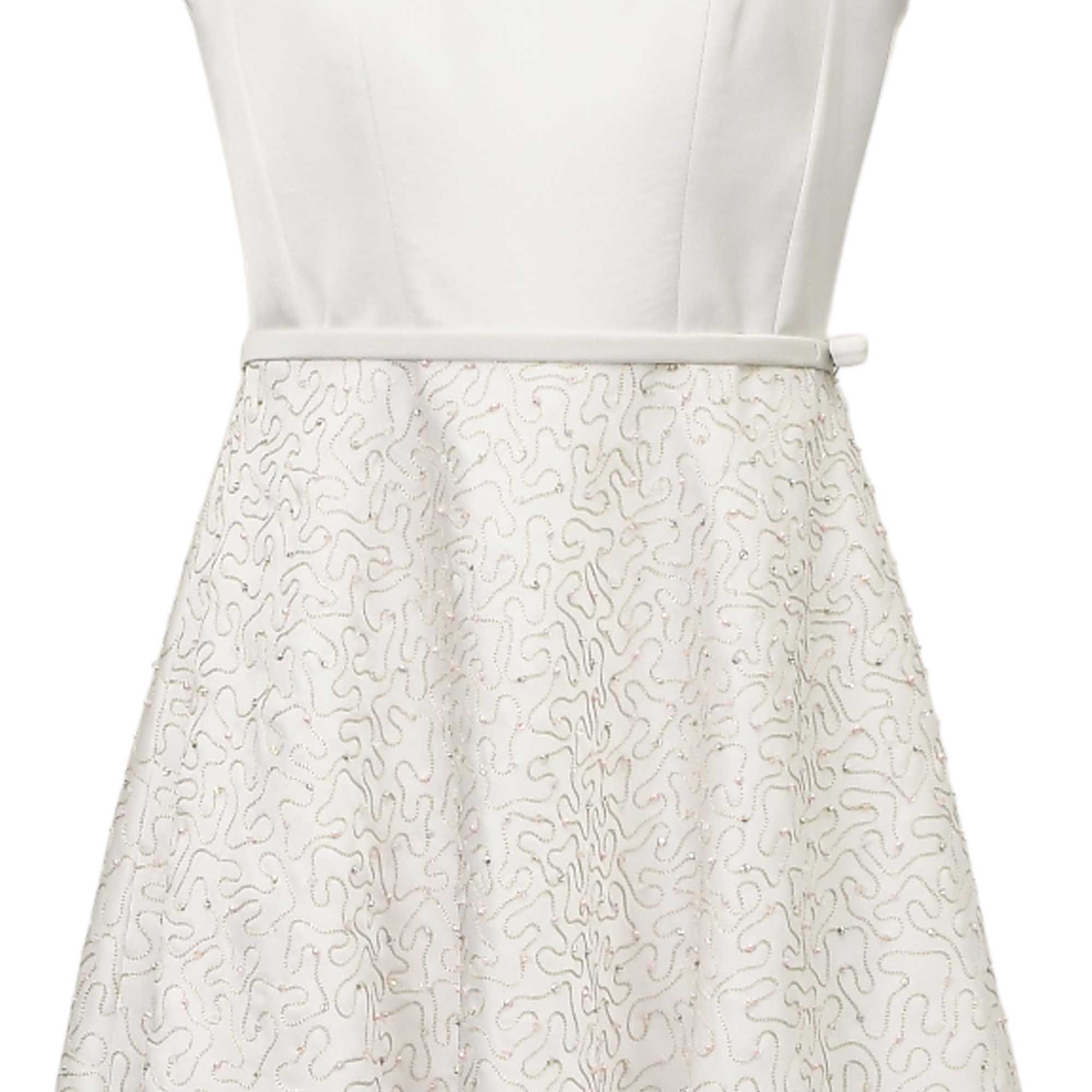 White dress with a plain bodice and a skirt featuring an intricate silver-toned beaded squiggly pattern with subtle pink acce