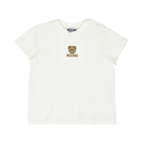 Close-up of the white short-sleeved baby T-shirt highlighting the embroidered Moschino Teddy Bear logo on the chest.