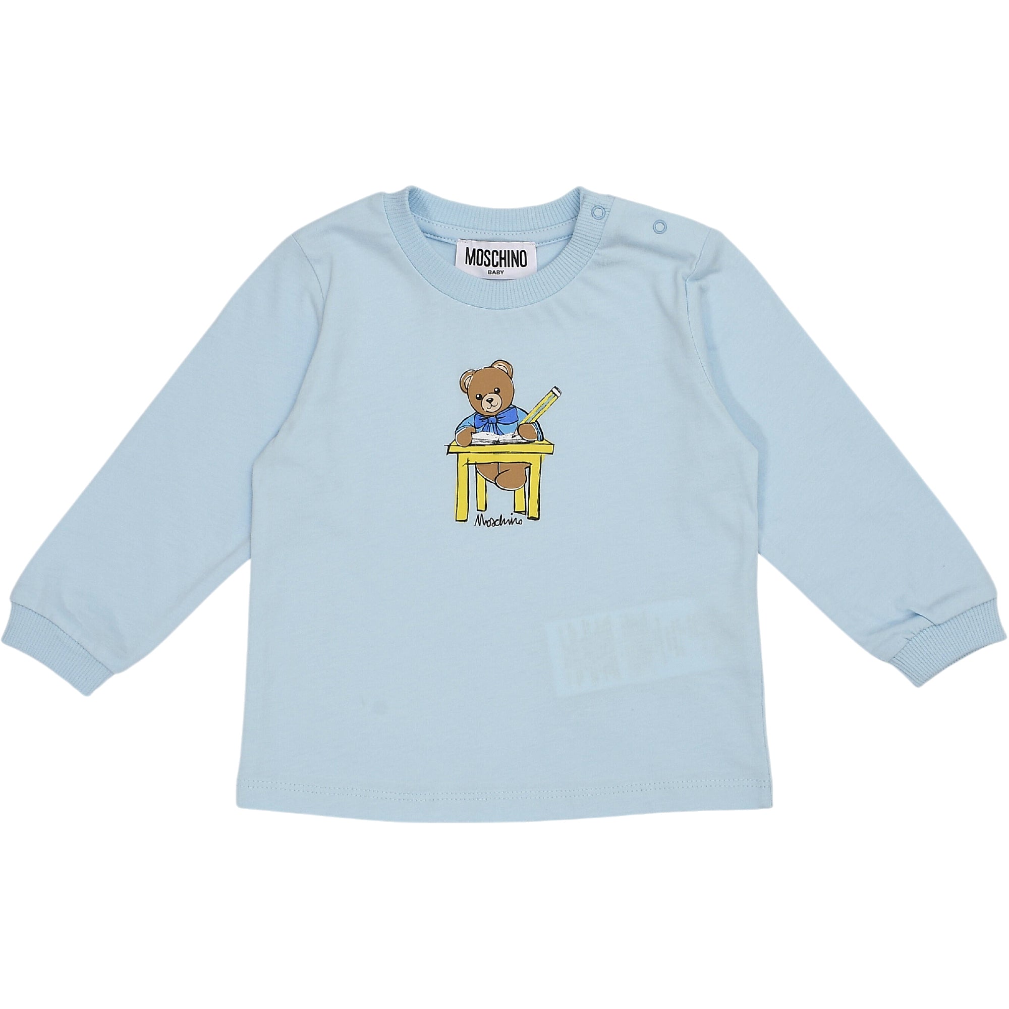 Light blue long-sleeved top with two shoulder snap buttons. Front features a graphic of a brown teddy bear at a yellow desk h