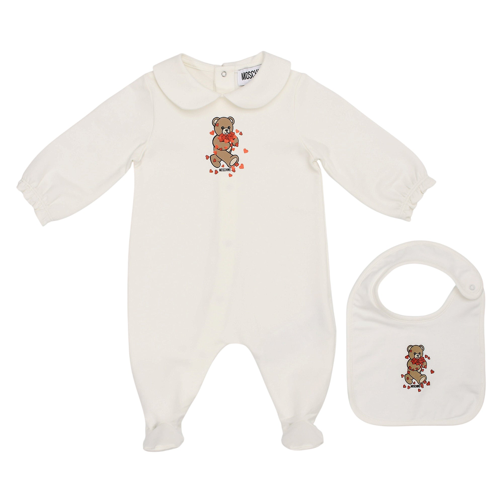 White Moschino Kids long-sleeved, footed sleepsuit with round collar and teddy bear heart print, plus matching bib.