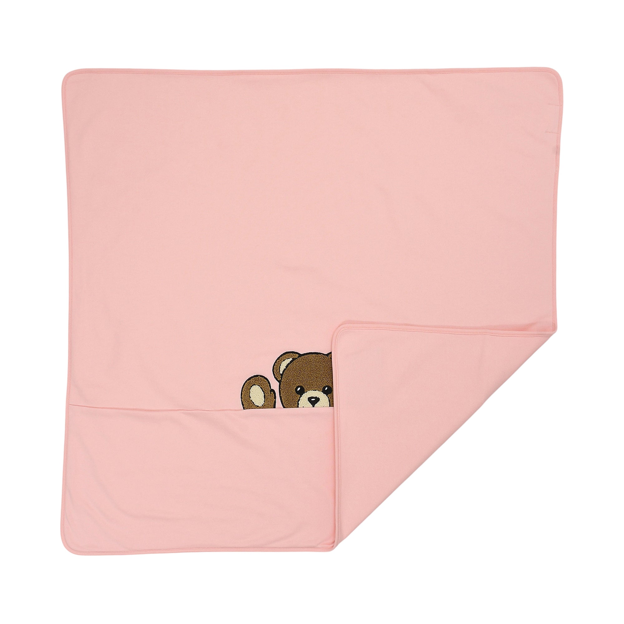 Pink blanket with a brown teddy bear peeking from a fold at the bottom. The bear has a tan snout and inner ears.
