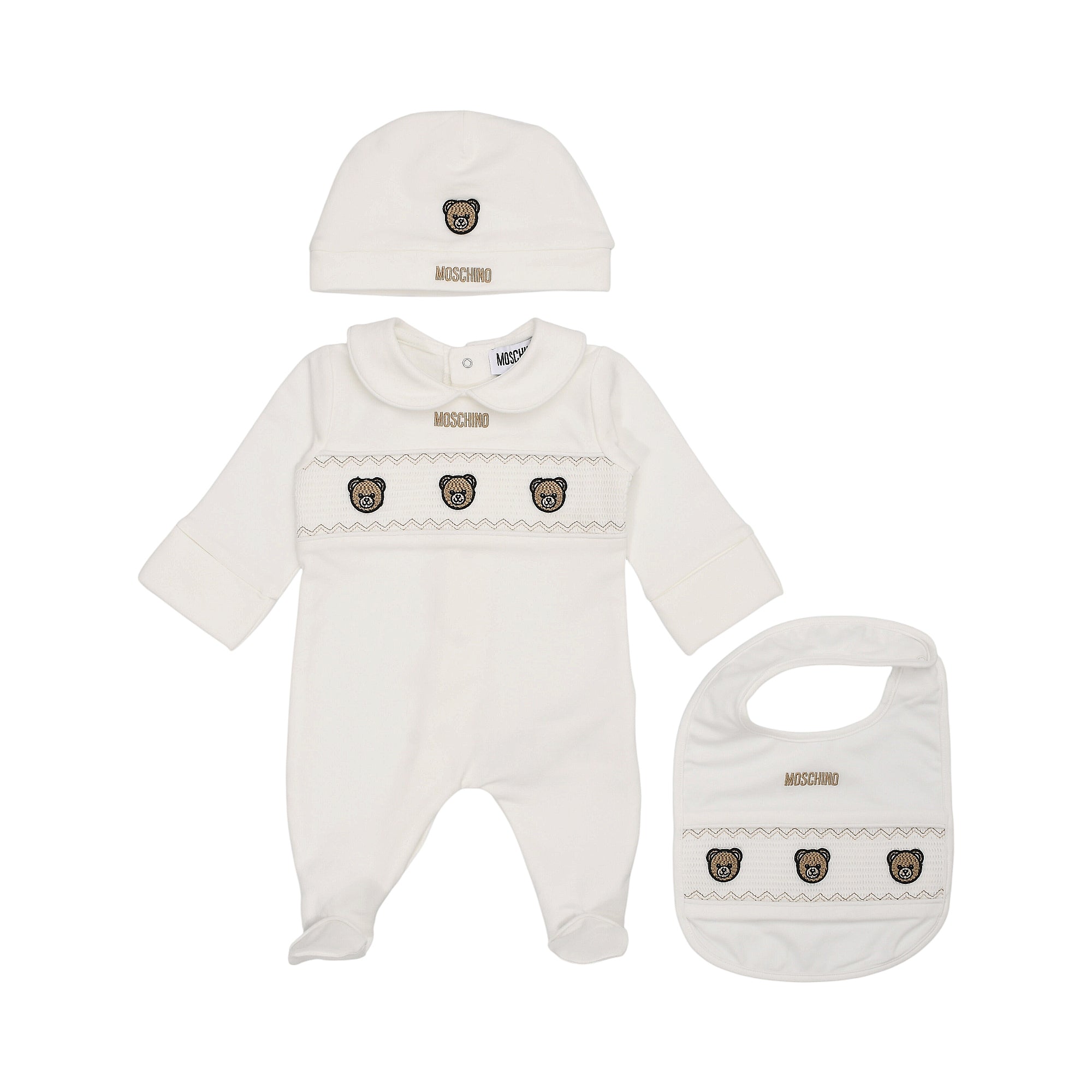 White Moschino Kids three-piece sleepsuit set including a footed sleepsuit, beanie hat, and bib, all with embroidered bear fa