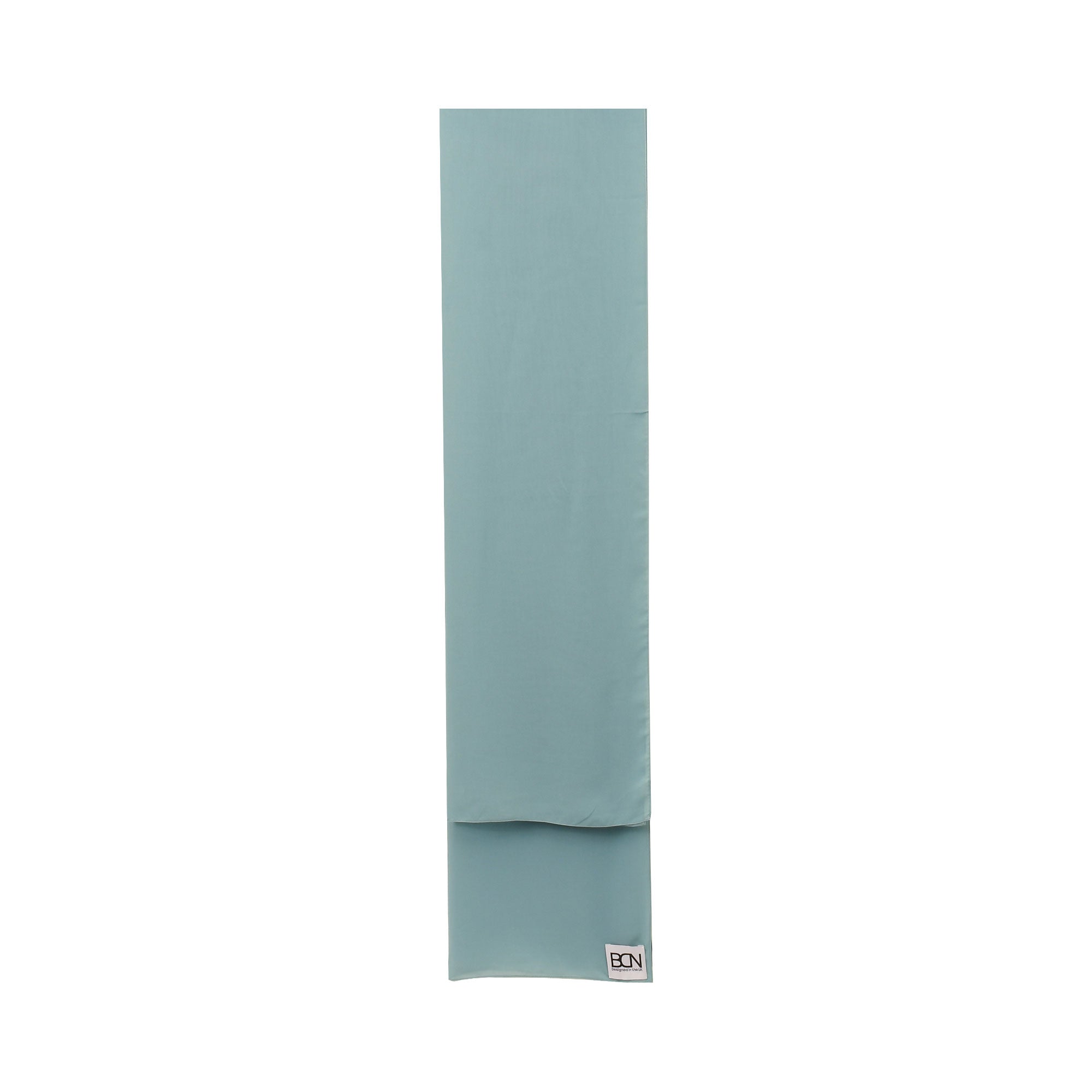 A folded muted blue-green abaya with a smooth texture and a small white 'BCN' tag visible at one end.