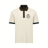 Cream pique polo shirt with dark brown collar, two-button placket, and dark blue ribbed cuffs. Features two embroidered chest