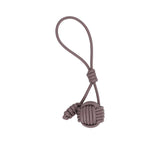 Leather bag charm by MUNI featuring a large spherical monkey fist knot at the bottom, smaller coiled knot accents, and a long attachment loop against a white background.