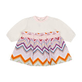 White long-sleeved baby dress with a pink trim crew neck and a pleated skirt featuring a multicoloured chevron pattern and pi