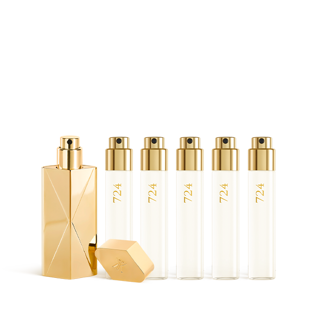 A luxury fragrance travel set featuring a sculptural gold travel spray case alongside five clear 11ml glass perfume refills labeled "724" with gold spray nozzles.