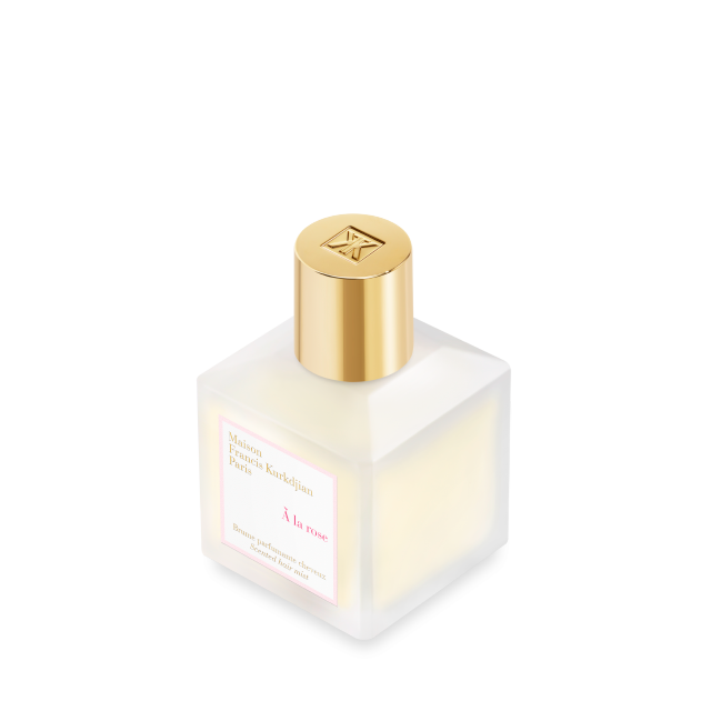 A angled view of  frosted glass bottle of Maison Francis Kurkdjian Paris "À la rose" Scented Hair Mist (70ml) with a gold cap and a white label featuring pink and gold lettering.