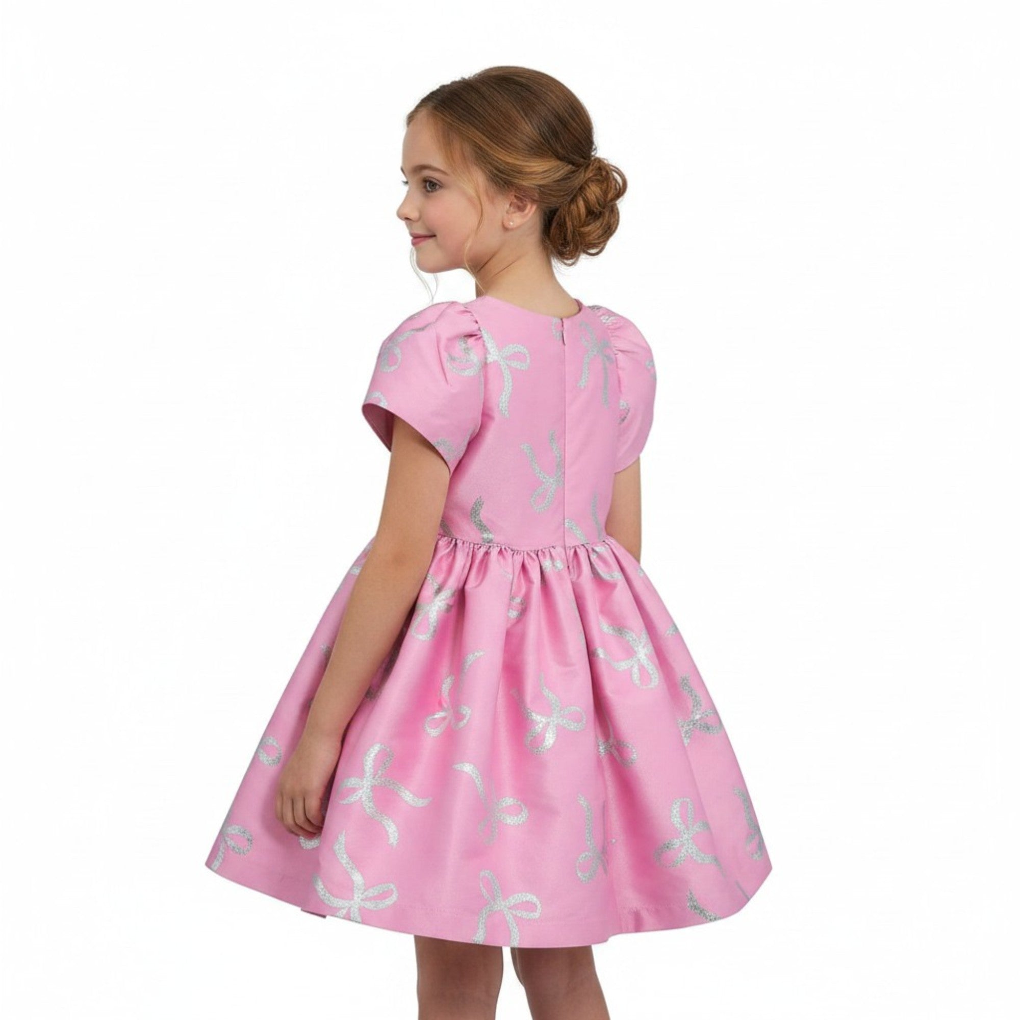 Young girl wearing a pink dress with white patterns on a white background.