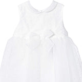 Close-up detailed shot of the Mamaluma girls white dress showcasing the intricate Swiss dot pattern fabric texture, Peter Pan collar, and central front waist bow.