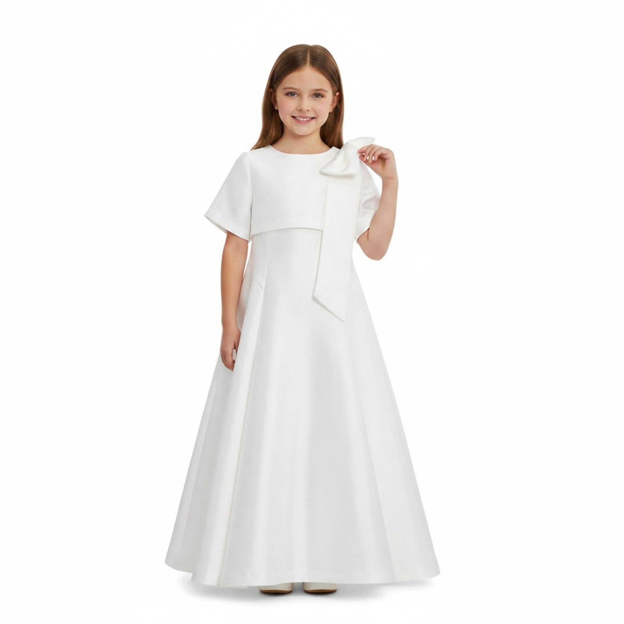 Studio model shot of a young girl wearing the Mamaluma white satin maxi dress, demonstrating its elegant floor-sweeping drape and structural shoulder bow detail.