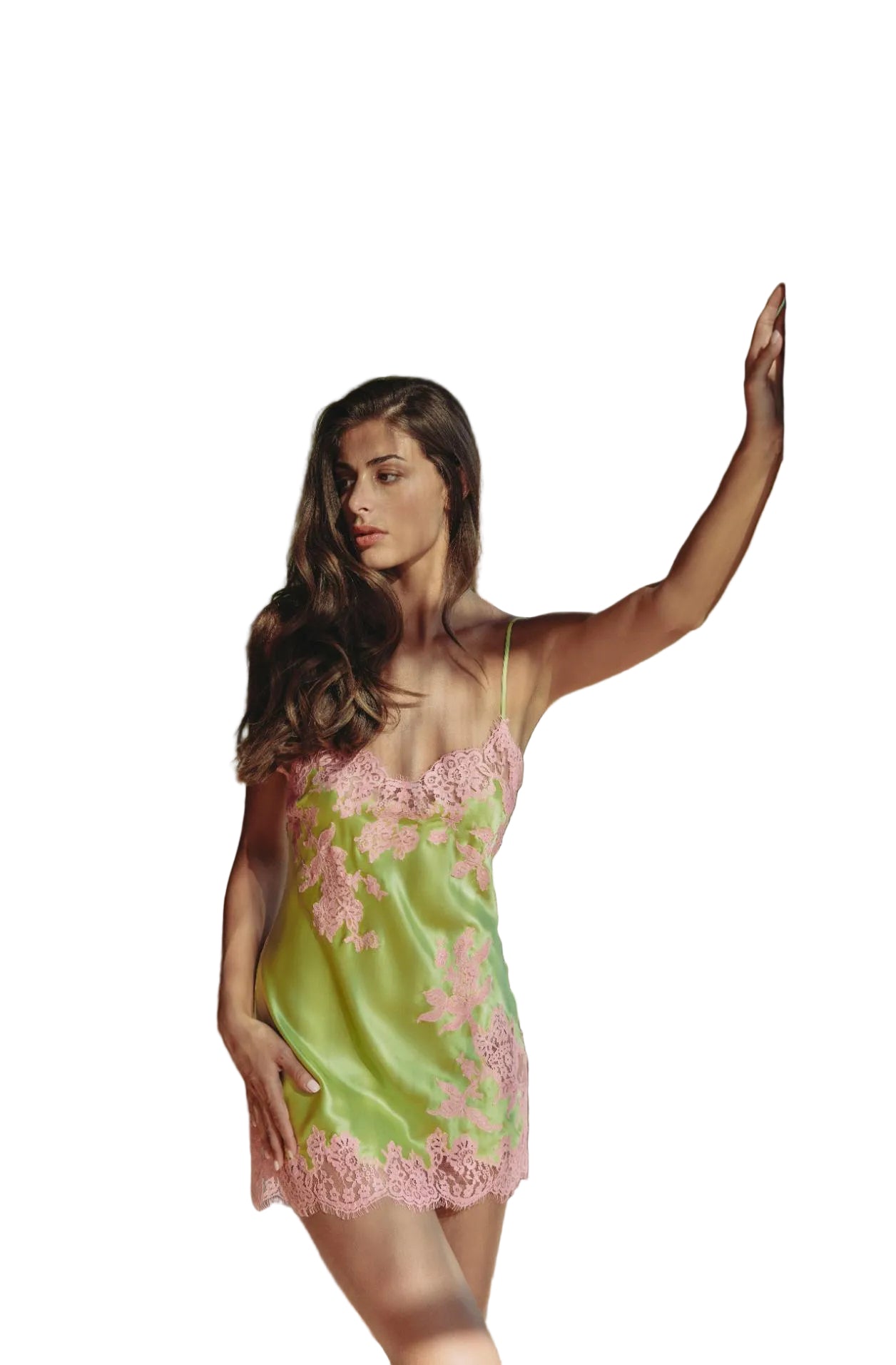 A woman wearing a lime green satin slip dress with pink floral embroidery and lace trim, posing on a balcony with lush green trees in the background.