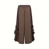 Rear view of Meimeij brown wide-leg trousers highlighting the gathered elasticated back waistband and the vertical arrangement of 3D floral appliqués on the lower legs against a white background.