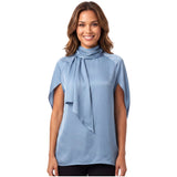 Front view of a smiling model wearing the Meimeij cornflower blue satin blouse showcasing its high neckline, integrated drape scarf, and open cape sleeves.